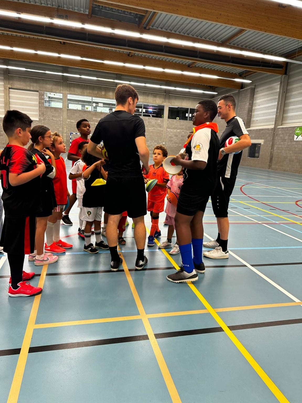 Enfants réunis autour de leurs formateurs pendant une séance B2B Football Academy